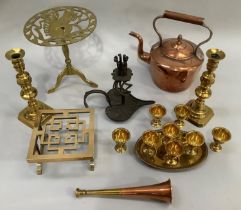 A copper kettle, a pair of brass turned candlesticks, two brass trivets, a copper and brass horn,