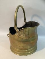 A brass coal scuttle with swing handle