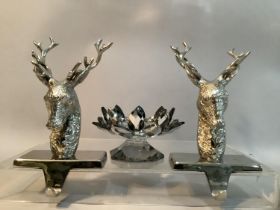A pair of white metal table hooks formed as stags together with a moulded glass candle holder in the