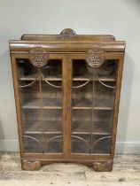 A 1940s oak book case having a short raised back above two tracery glazed doors with grape vine