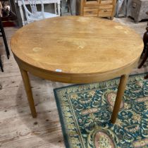 A teak extending dining table by Nathaniel with cross banded surface, moulded apron and on tapered