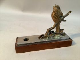 A pen holder fashioned as a gilt bronze figure of a bird perched on a branch, mounted on a steel and