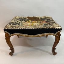 A Victorian walnut stool, rectangular having the original floral needlework cover and on moulded