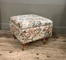An upholstered box foot stool on turned legs with brass caps and casters with Scotch Guard