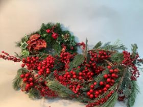 A large faux foliage Christmas garland with berries and a Christmas wreath