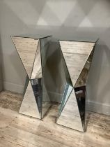 A pair of mirrored plinth of square outline and waisted columns with angled panels, 33cm x 33cm x