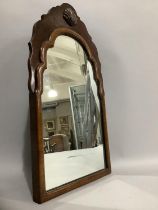 An early 20th century walnut shield shaped mirror having a carved shell pediment, 57cm x 33cm