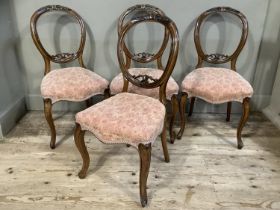 Four Victorian mahogany balloon back chairs, foliate carved, upholstered serpentine seats and on