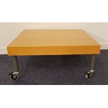 BEECH OCCASIONAL TABLE on stout metal supports with casters, 80cm wide
