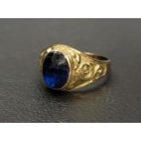 FACETED BLUE GLASS DRESS RING in unmarked high carat gold with scroll decorated shoulders, ring size
