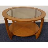 TEAK CIRCULAR OCCASIONAL TABLE with an inset smoked glass top on shaped supports united by a
