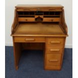 OAK ROLL TOP DESK with a tambour front opening to reveal pigeon holes and drawers, the base with a