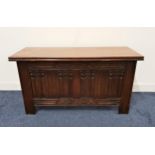 OAK COFFER with a lift up lid above a carved linen fold front panel, standing on plain supports,