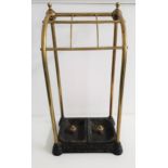 BRASS AND CAST IRON STICK STAND with six open sections above two removeable drip pans, 63.5cm high