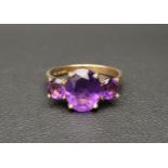 GRADUATED AMETHYST THREE STONE RING the central oval cut amethyst approximately 2.5cts flanked by