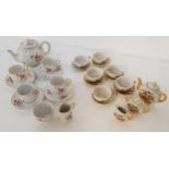 CHILD'S POTTERY TEA SET with a white ground and floral motifs, comprising four cups and saucers,