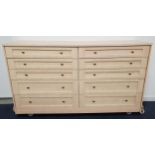 LARGE LIGHT OAK EFFECT CHEST OF DRAWERS with an arrangement of ten drawers, standing on a plinth