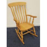 BEECH ROCKING CHAIR with a slatted back and shaped arms, on turned supports and shaped rockers