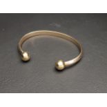 NINE CARAT GOLD CUFF BANGLE the rounded bangle with ball finials, approximately 21.9 grams