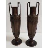 PAIR OF BRONZE URNS of slender amphora form, each with twin handles and decorative panels to the