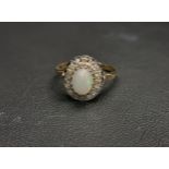 OPAL AND DIAMOND CLUSTER RING the central oval cabochon opal approximately 0.75cts in sixteen