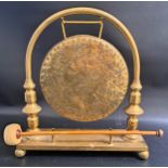 BRASS TABLE GONG with a rectangular base on ball supports, with an arched suspension arm with a