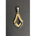 DIAMOND SET NINE CARAT GOLD PENDANT of shaped design with pierced centre, 3cm high including