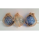 THREE GLASS FISHING NET FLOATS two blue glass and one clear glass, in net bags (3)