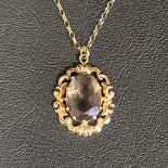 SMOKY QUARTZ PENDANT the oval cut quartz in nine carat gold pierced scroll decorated mount, on