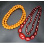 TWO AMBER COLOURED BEAD NECKLACES the cherry coloured graduated example with oval beads ranging