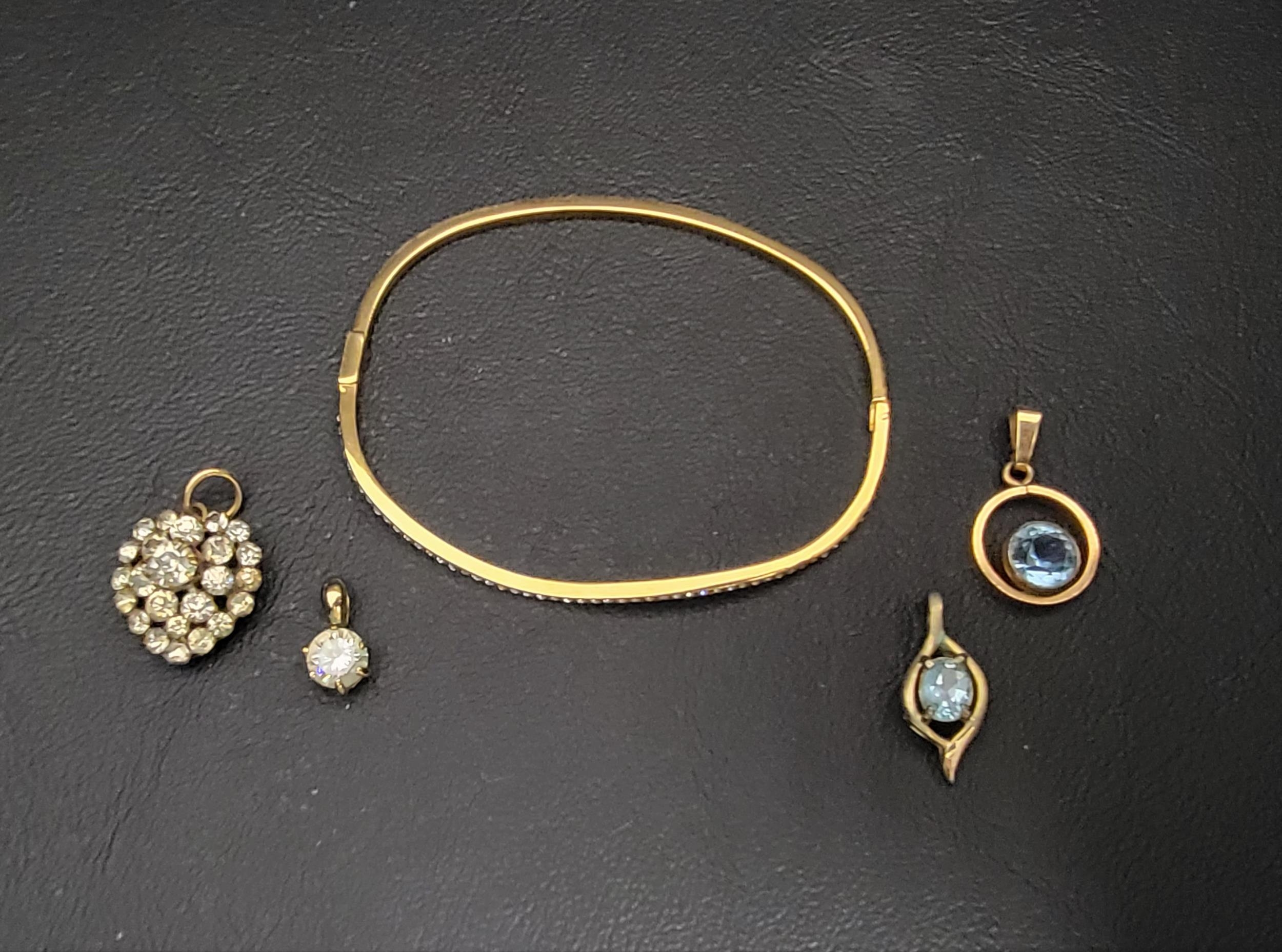 FOUR GOLD PLATED PENDANTS AND A BANGLE the wavy bangle set with CZ, the pendants of various