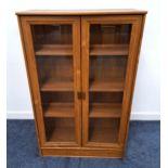 TEAK EFFECT BOOKCASE with a rectangular top above two glass panel doors opening to reveal a shelved