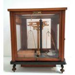 SET OF OERTLING SCIENTIFIC SCALES model 48G.C, in a mahogany and glass case with a selection of