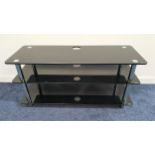 TELEVISION STAND with three black glass shelves with tubular steel supports, 53cm x 110cm