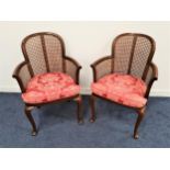 PAIR OF MAHOGANY ARMCHAIRS with shaped caned backs, arms and seats with cushions, standing on