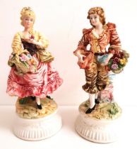PAIR OF ITALIAN FIGURINES depicting a man and lady, raised on circular bases and both carrying a