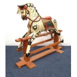 20th CENTURY WOODEN ROCKING HORSE with a dapple grey body and red corduroy saddle with adjustable