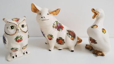 THREE POTTERY ANIMALS decorated with orchard fruit, comprising a duck, 21.5cm high, a seated pig,