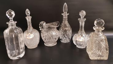 FIVE VARIOUS CUT GLASS DECANTERS and stoppers, two with porcelain decanter labels, brandy and