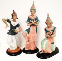 THREE POTTERY SIAMESE DANCERS in traditional dress, raised on wooden plinths, 52cm, 44cm and 40.
