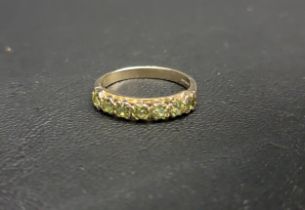 PRETTY PERIDOT HALF ETERNITY BAND RING with seven round cut peridots, on a nine carat gold shank,