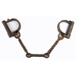 18th century leg irons. A pair of wrought iron, locking shackles linked by three twisted iron links.