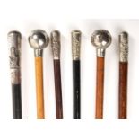 A collection of six regimental swagger sticks, each with a white metal cap, relief decorated with