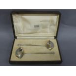 Omar Ramsden - A pair of silver sauce ladles with scroll foliate finials, tapering ribbed handles