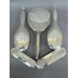 Omar Ramsden - A five piece silver backed dressing table set with chased wild rose decoration and