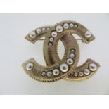 Chanel double C emblem in gilt metal and imitation pearl brooch width 5 cms. in Chanel black pouch