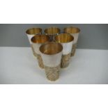 A set of six Stuart Devlin parcel gilt silver beakers with blind fretwork decoration to lower half
