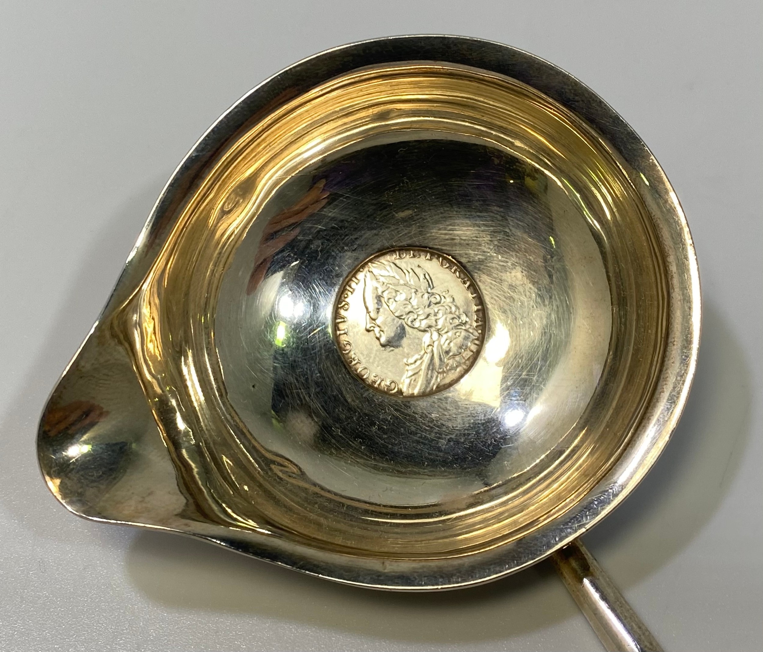 A George II silver toddy spoon, the bowl inset with a silver shilling and turned horn handle,