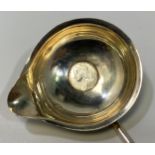 A George II silver toddy spoon, the bowl inset with a silver shilling and turned horn handle,