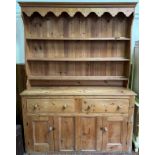 A large sripped and waxed pine kitchen dresser, with shaped frieze above a boarded raised back